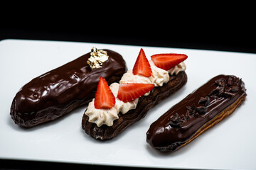 Eclairs of different flavors set on a dark background for a restaurant menu