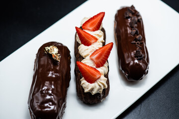 Eclairs of different flavors set on a dark background for a restaurant menu