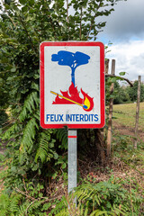 
"Prohibited fire" sign written in French in a countryside landscape. No fire sign with lit match . Fires not allowed. 