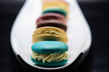 Macaroons of different flavors set on a dark background for a restaurant menu