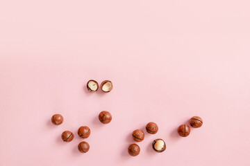 Cracked macadamia nuts on pink background with copy space