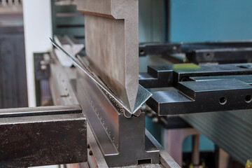 Bending sheet metal on a hydraulic machine at the factory. Close-up.