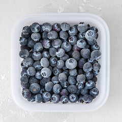 Frozen blueberries in the tray on a concrete background.