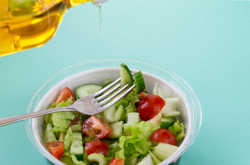 Healthy food concept. Green vegan salad from green leaves mix and vegetables on light blue background