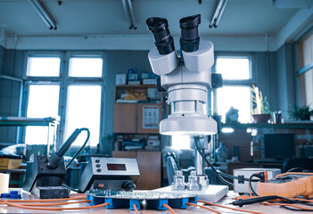 Modern microscope, connectors component and large green microcircuit in workshop laboratory