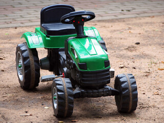 A children's toy tractor with a pedal drive stands on the Playground. Educational toys for children, outdoor activities. © wpg77