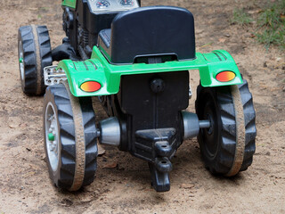 A children's toy tractor with a pedal drive stands on the Playground. Educational toys for children, outdoor activities.