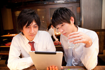居酒屋でタブレットＰＣを見るビジネスマン