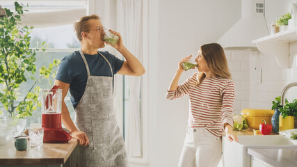 Handsome Young Man in Glasses Wearing Apron and Beautiful Girl are Making A Smoothie in the...
