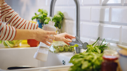Close Up Shot of a Woman Filling a Reusable Plastic Bottle with Clean Filtered Tap Water. Using...