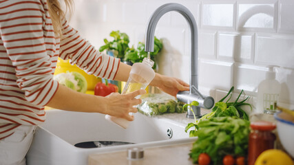Close Up Shot of a Woman Filling a Reusable Plastic Bottle with Clean Filtered Tap Water. Using Sports Bottle for Hydration in a Modern Kitchen. Natural Clean Diet and Healthy Way of Life Concept.