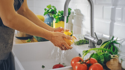 Close Up Shot of a Person Washing Yellow Sweet Pepper with Tap Water. Authentic Stylish Kitchen with Healthy Vegetables. Natural Clean Products from Organic Farming Washed by Hand.