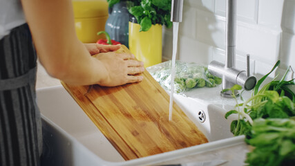 Close Up Shot of a Person Washing a Chopping Board with a Cleaning Liquid Under Tap Water. Using...