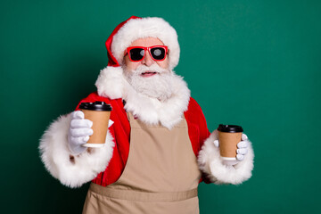 Portrait of his he nice handsome bearded cheerful fat Santa grandfather waiter worker wearing apron giving you latte cup selling beverage share point shop take away out isolated green color background