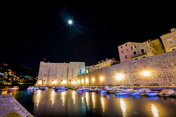 Port with motion blurred boats and light diffraction, long exposure at night. Scenery winter view...
