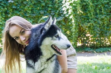 attractive blonde hugs her dog in the park.