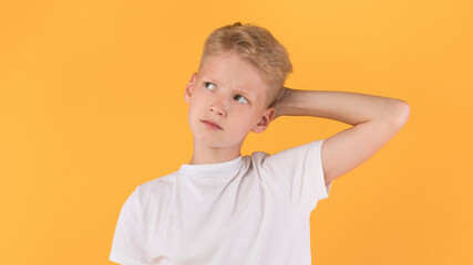 Confused puzzled male kid scratching head at studio