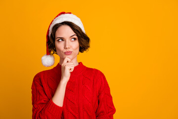 Photo of funny pretty lady celebrate winter holidays dreamy look empty space think family party hand on chin x-mas concept wear santa cap red knitted sweater isolated yellow color background