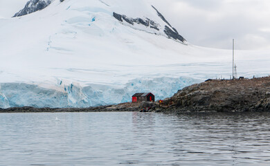 Antarctica, Peninsula: On Wiencke Island in Februar 2020. Wooden building and Penguins at Port Lockroy