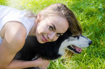 attractive blonde hugs her dog in the park.