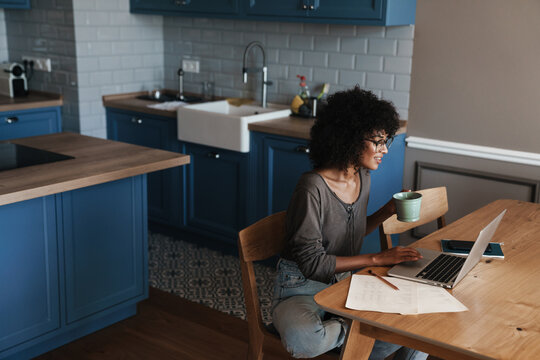 Image of woman drinking coffee while working with laptop