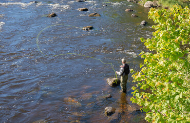 Flyfisherman using flyfishing rod in a river. Farnebofjarden national paek in Sweden.