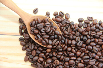 natural black coffee beans in a wooden spoon