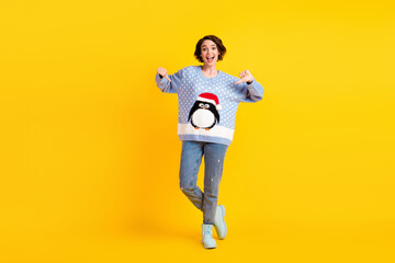 Fototapeta na wymiar Full size photo of pretty charming lady x-mas party direct fingers showing friends new jumper funky cute fluffy penguin wear ugly ornament sweater jeans boots isolated yellow color background