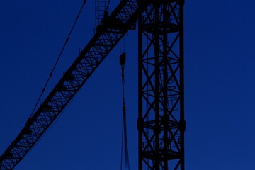 Fototapeta na wymiar Construction crane in backlight, evening light, intense blue sky.