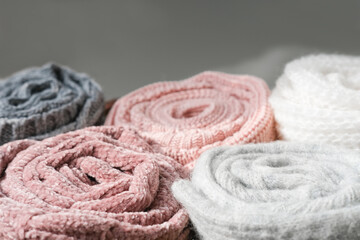 Obraz na płótnie Canvas rolled knitted sweaters in grey and pink tones. autumn and winter warm pullovers. textured background. cozy clothes for cold season.