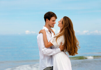 Cute couple of young people in love hugging on the sea coast