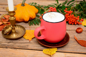 Composition of cup, mug of coffee, latte and candlestick with pumpkin, yellow leaves and rowan on wooden background. Autumn  card, composition, mood. 