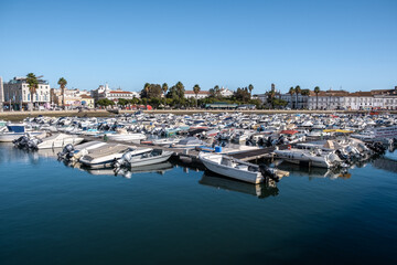 Fototapeta na wymiar Boats At The Marina Of Faro With Water Reflection And Clear Blue Sky In Algarve, Portugal.
