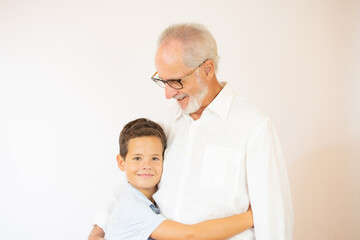 Smiling boy hugs his grandfather on white background