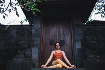 Young fit woman relaxing while practicing yoga among ancient statues