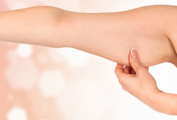 Woman holding her hand with excess fat against an abstract background with light flares and...