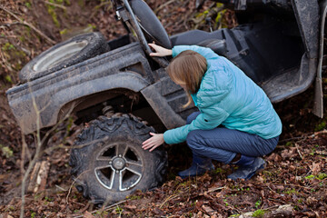 A woman checks the tires of a buggy that has rolled down a mountain into a ditch. Ekstrmelnaya riding ATV