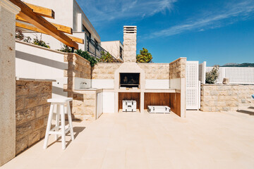 Grill area in the villa by the sea. A large courtyard with a stone grill and an open white stone...