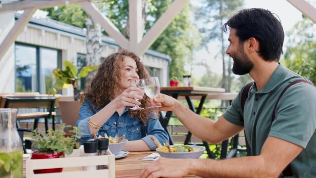 Happy couple sitting outdoors on terrace restaurant, having lunch.