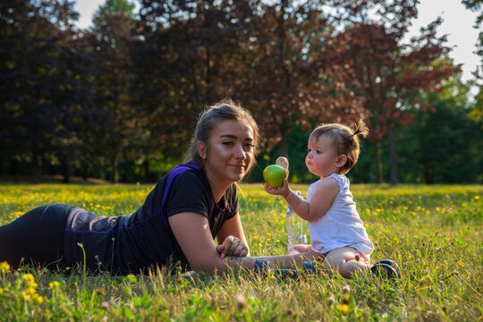 Young mother with her child do sports in the park.