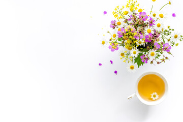 Wild flowers bouquet with cup tea on a table, top view