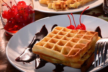 sweet belgian waffles with cherries on a wooden table