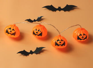 Halloween pumpkin lights and black paper bats on orange background with copy space. Halloween  concept.