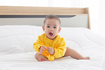 Fototapeta premium Asian babies are playing baby toys in bed.
