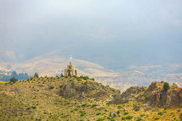 Fototapeta na wymiar Chapel and cross in the mountains in Lebanon. Panoramic view of the Kadisha Valley. The place of the ancient Christian community. Beautiful Lebanese mountain landscape