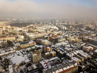 Fototapeta na wymiar Aerial black and white winter top view of modern city center with tall buildings and parked cars on snowy streets.