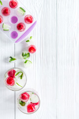 Raspberry and lime in ice cubes on white table top view copy space