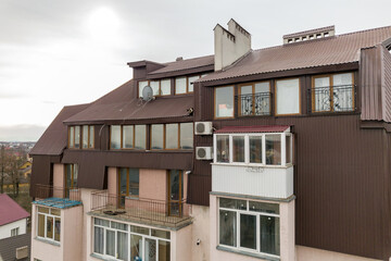 High apartment building with many windows and metal sheets roof.