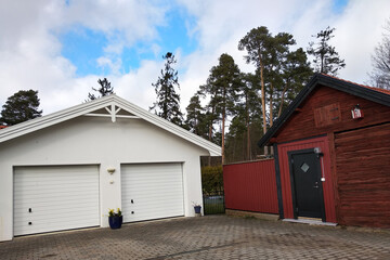 Fototapeta na wymiar White new garage for two cars and wooden barn on private house yard.