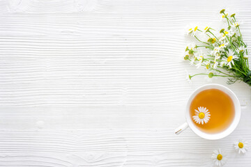 Fototapeta na wymiar Herbal tea with chamomile flowers, top view copy space